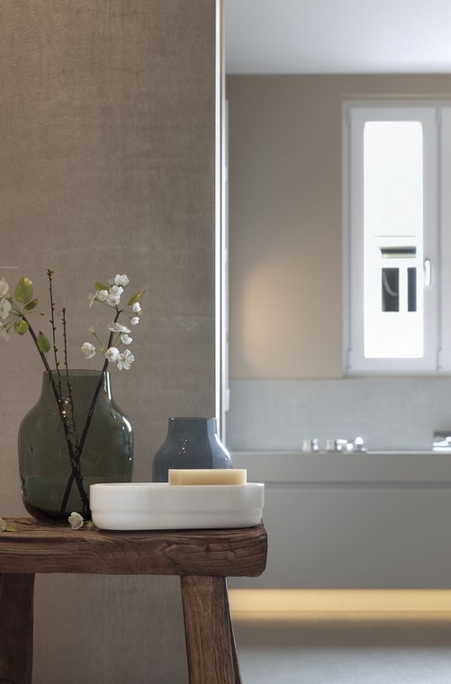 Product visualization of a modern bathroom in Frankfurt – close-up of decorative glass vases and soap on a rustic wooden table with bathtub view, created by gmsvision.