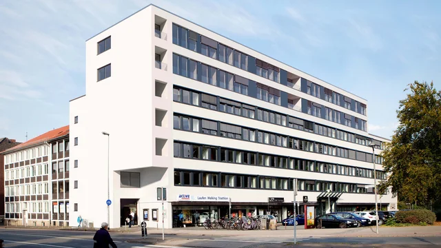 Architekturvisualisierung des modernen Wohn- und Geschäftshauses in der Blissestraße 5 in Berlin, mit klarer weißer Fassade, großen Fensterfronten und urbanem Straßenumfeld.
